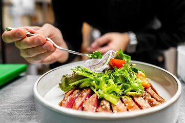 Close-up of a fresh salad with tuna, mixed greens, cherry tomatoes, and sliced onions being served.