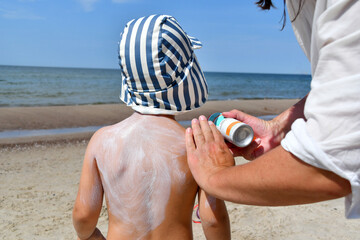 Mother applying sunscreen protection creme on little boy back
