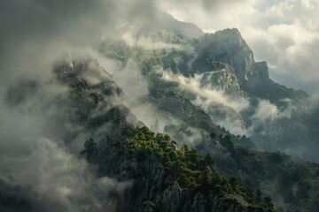 Obraz premium Misty mountain peaks shrouded in clouds, with lush green forests clinging to rocky slopes.