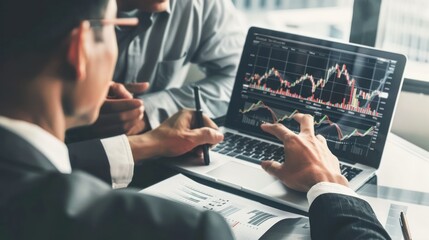 Two diverse business men discussing financial market data using laptop and digital tablet. Financial advisor broker manager consulting investor client about digital investment at office meeting.