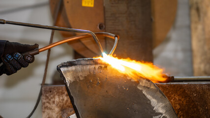 A person is using a blowtorch to heat a piece of metal