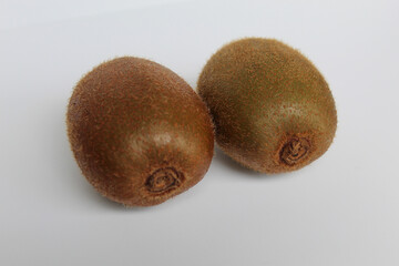 Two uncut kiwi fruits isolated on white background