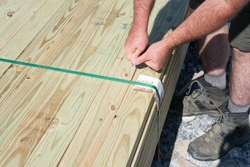 Man's hands cutting a band around a stack of lumber with a pocket knife.