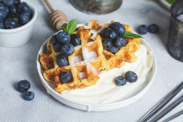 Belgian waffles with sour cream and blueberries in a plate