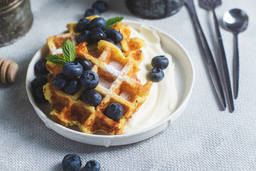Belgian waffles with sour cream and blueberries in a plate