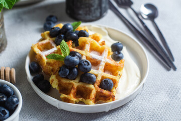 Belgian waffles with sour cream and blueberries in a plate