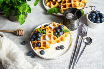 Belgian waffles with sour cream and blueberries in a plate