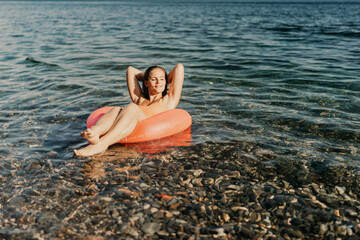 A woman is floating on a red inflatable tube in the ocean