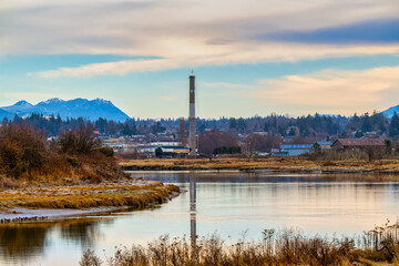 2022-12-04 THE STILLAGUAMISH RIVER WINDING THROUGH STANWOOD WASHINGTON WITH A SMOKE STACK AND BUILDINGS IN THE BACKGROUND NEAR CAMANO ISLAND WASHINGTON