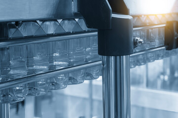 The  empty drinking water bottles  hanging on the conveyor belt for filling process.