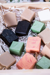 Handmade soaps in a wooden box, showcases an assortment of colorful, handcrafted soaps in various shapes and sizes, arranged in a wooden box with shredded paper. 