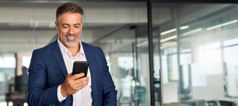 Banner, copy space with mature trader businessman holding smartphone in office. Middle aged manager using cell phone mobile trading app. Digital technology application and solutions for trade business