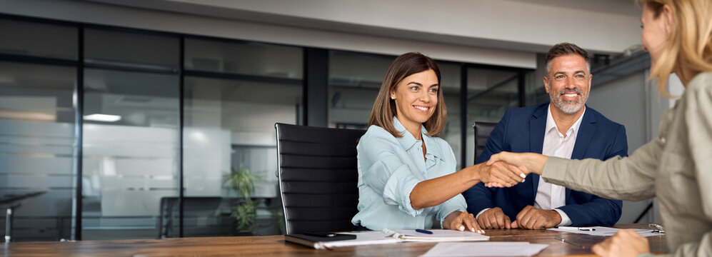 Latin business team of woman and European man shaking hands with colleagues, partners or employees, signing a contract. Group of people satisfied with results of team work together. Banner, copy space