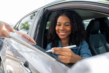 African American woman  rents a car and sign a contract with a digital pen on a digital tablet screen. Business car rental, sale man giving auto key of vehicle to customer renter.