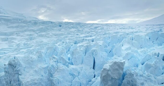 Calving blue glacier close up in Perito Moreno. Snow mass wall towering cold ocean. Massive snow covered iceberg floats cold water. Ecology, melting ice, climate change, global warming. Explore travel