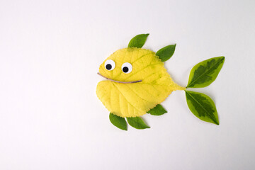 a fish made from leaves and other natural materials. The main body of the fish is crafted from a...