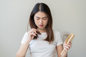 Damaged Hair, frustrated asian young woman, girl hand in holding brush splitting ends messy while combing hair, unbrushed dry long hair. Health care beauty, portrait isolated on white background.