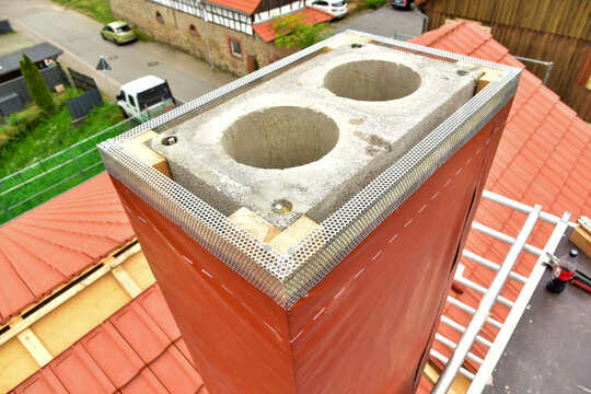 Neu aufgebauter Beton-Sandstein mit zwei Schamotte-Innenrohren mit Baustahl-F&uuml;hrungen, Abschlussfolie und Abschlussprofil zum Feuchtigkeitsschutz am Schornstein-Kopf