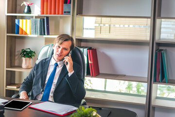 Happy businessman smiling and using smart phone while relaxing working on a comfortable place at office