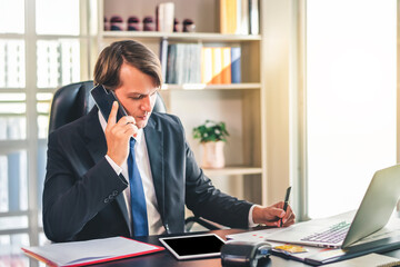 Happy businessman smiling and using smart phone while relaxing working on a comfortable place at office