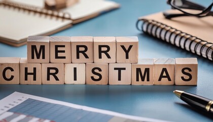 merry chrstmas word written on wooden blocks on blue office table with calendar. 