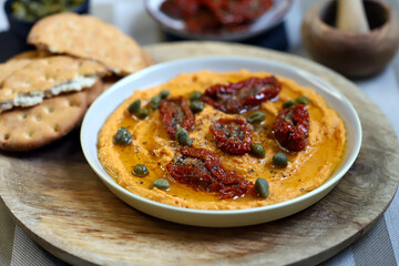 Hummus with sun-dried tomatoes and capers on a plate