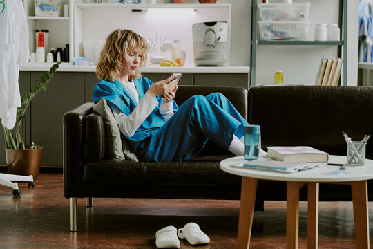 Pretty blonde Caucasian nurse surfing Internet while having break and spending it in on call room