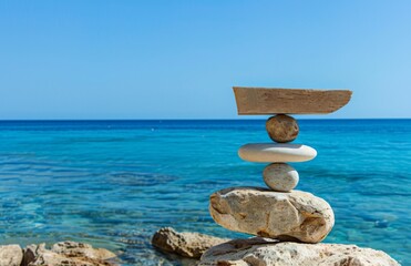 Balanced Rock Scale with Leaning Stones Against Clear Blue Sky and Ocean Horizon. Symbolizing Life Balance, Harmony, and Emotional Peace through Personal Growth