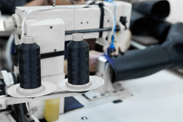 Fototapeta premium Sewing machine in the leather workshop is in action, hands are working on leather parts for shoes.