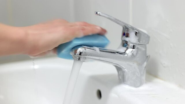 Cleaning the sink and faucet in the bathroom close-up. Concept of cleaning company services, hygiene and cleanliness.