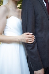 Unrecognizable bride and groom in elegant wedding outfits standing together during ceremony on sunny day.