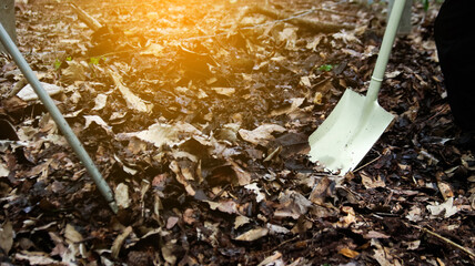 Hands holding shovel to mix raw materials including dried leaves and dung