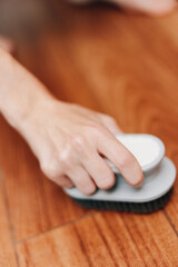 Fototapeta premium Person cleaning wooden floor with a brush, white object on top