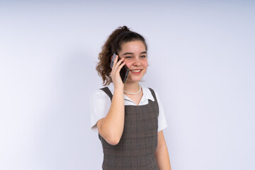 Happy beautiful young woman teenager with long curly hair holding mobile phone