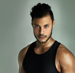 Fototapeta premium Man, serious portrait and bodybuilder in studio, strong muscle and body training on gray background. Male person, athlete and confidence for fitness results, wellness and face for sports workout