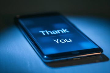 Smartphone screen displaying "Thank You" message in dark setting, symbolizing gratitude and appreciation. The modern and simple design emphasizes the importance of expressing thanks in the digital age