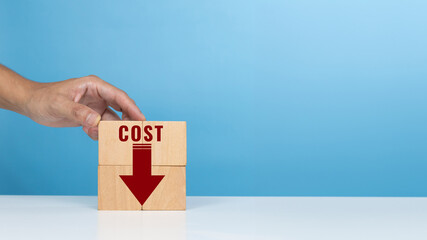 Concept of cost, lean or cost reduction. Hand hold wooden block with the word cost and down arrow for decreasing expense to maximize profits
