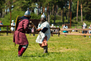 A historical reenactment of a Middle Ages battlefield. Men in armor fighting each other. 