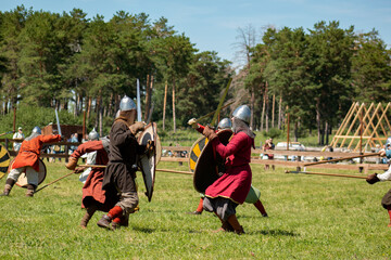 A historical reenactment of a Middle Ages battlefield. Men in armor fighting each other. 
