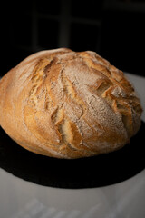 Beautiful freshly baked yeast-free round bread on the table on a black base. Fragrant, delicious sourdough bread. Close-up. Healthy nutrition concept. Vertical photo.