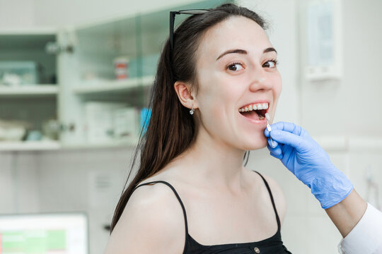 Dentist checking tooth shade for female patient in clinic - Powered by Adobe