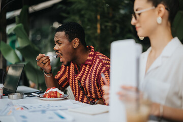 Businesspeople having a lunch break at an outdoor workspace, with a man eating and a woman holding documents. The serene environment promotes a productive and relaxing work setting.