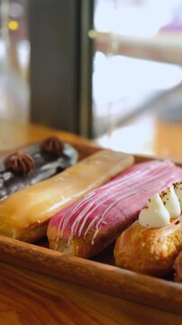 delicious eclairs are on the table. Variety of eclairs with glossy chocolate topping, lined up neatly on a rustic wooden table