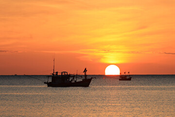 Silhouette of a fishing boats laying nets in the morning at Prachuap bay, Prachuap khiri Khan Province, Thailand 