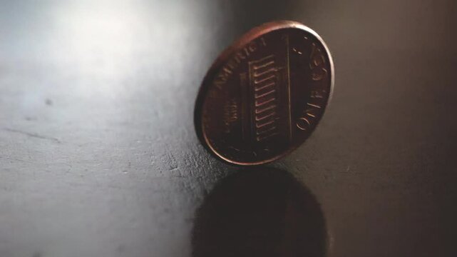 Copper penny spinning on a wooden tabletop in slow motion; 240fps 4k footage