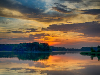 Serene Fishing Lake: A peaceful scene by the tranquil waters of a secluded fishing lake. Surrounded by lush greenery and framed by a clear blue sky, this picture captures the essence of a perfect day 