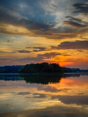 Serene Fishing Lake: A peaceful scene by the tranquil waters of a secluded fishing lake. Surrounded by lush greenery and framed by a clear blue sky, this picture captures the essence of a perfect day 