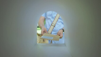 Hands of postal worker taking envelopes from bag and placing them into mailbox while delivering correspondence. View from inside of mailbox