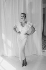 Black and white photo of an elegant woman with blonde bob haircut and red lipstick posing in a...