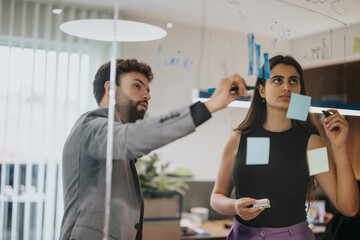 Two business professionals, one European male and Indian female, engaged in brainstorming and...